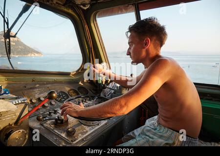 Un uomo caucasico nella cabina di guida di una grande locomotiva che guarda fuori dal finestrino Foto Stock