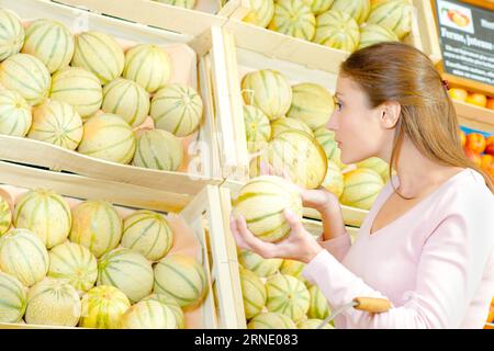 Signora odore di melone al negozio di generi alimentari Foto Stock