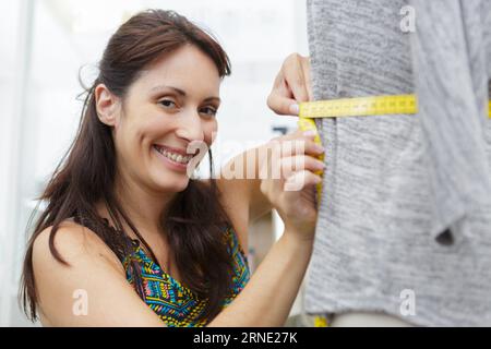 dressmaker taking waist measurement on mannequin Stock Photo