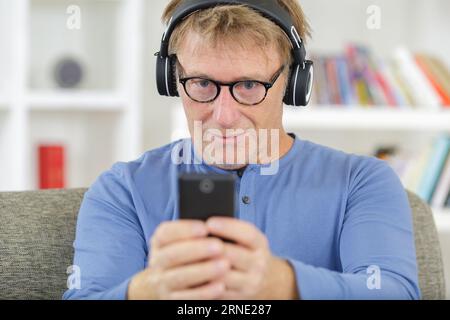 cheerful mature man listening to music from smartphone Foto Stock