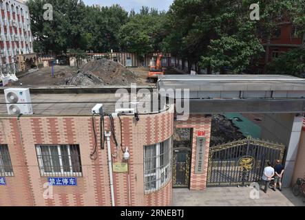 Un escavatore viene utilizzato per smantellare l'autodromo presso il campus Baiyunlu della Beijing No. 2 Experimental School nel distretto di Xicheng a Pechino, in Cina, il 17 giugno 2016. Il campus Baiyunlu della Beijing No. 2 Experimental School ha iniziato a rimuovere una pista sintetica dopo che sostanze tossiche presumibilmente avvelenavano dozzine di studenti, le autorità locali hanno confermato venerdì. Il mese scorso molti studenti della scuola hanno sofferto di sanguinamento dal naso, incantesimi vertiginosi e tosse dopo aver corso in pista. Anche se i risultati dei test ufficiali hanno mostrato che la pista era all'altezza dello standard per l'uso, molte persone lo hanno messo in dubbio e investiga Foto Stock