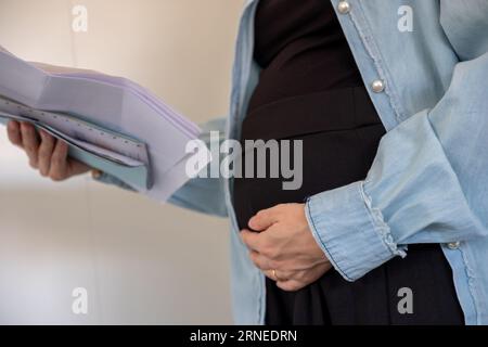 Donna incinta che detiene una ricevuta su sfondo bianco Foto Stock