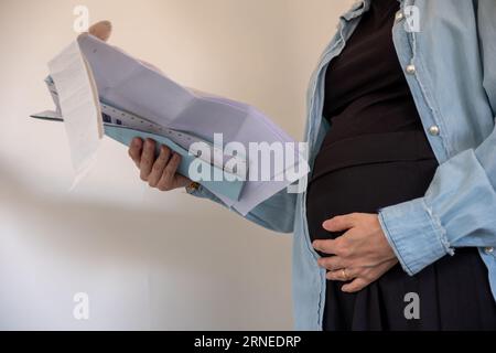 Donna incinta che detiene una ricevuta su sfondo bianco Foto Stock