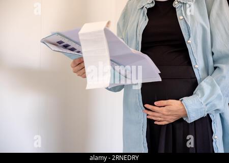 Donna incinta che detiene una ricevuta su sfondo bianco Foto Stock