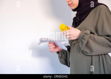 Supplemento di tenuta femminile incinta con esso è conto su sfondo bianco Foto Stock