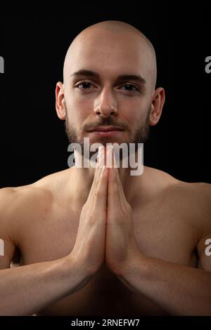 Giovane turco con le mani stringute prega dio mentre guardi la macchina fotografica con il volto pieno di speranza e fede Foto Stock