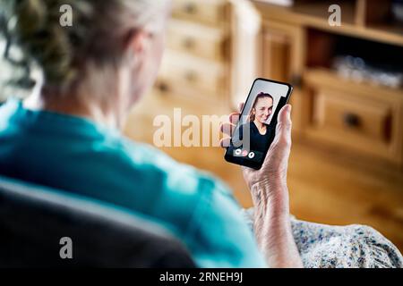 Vecchia donna anziana che ha una videochiamata telefonica con la giovane donna. Comunicazione familiare. Tecnologia mobile. Nonna che usa la videocall per smartphone. Foto Stock