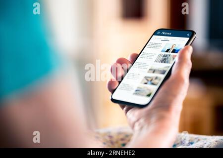 Notizie online. Schermo del telefono cellulare. Donna anziana che legge un giornale sul portale web e sul sito web. Ultime informazioni giornaliere. Titoli su Internet. Foto Stock