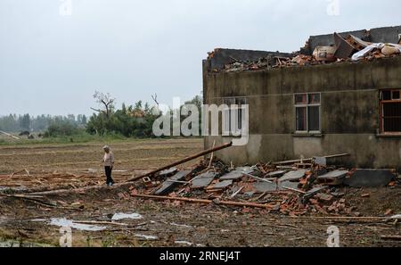 (160624) -- YANCHENG, 24 giugno 2016 -- la cittadina di 78 anni Gao Weilan cammina davanti alla sua casa nel villaggio Danping di Chenliang Township a Funing, Yancheng, nella provincia di Jiangsu della Cina orientale, 24 giugno 2016. Un totale di 98 persone sono state uccise dopo gravi tempeste in diverse città di Jiangsu giovedì, il quartier generale locale di soccorso ha detto venerdì. Circa 846 persone hanno subito ferite, 200 delle quali sono state gravemente ferite, ha detto. Più di 8.600 case, due scuole elementari e otto fabbriche furono danneggiate nelle contee di Funing e Sheyang, e in parti della città di Yancheng lungo la costa orientale di C. Foto Stock