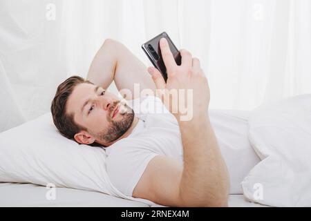 l'ossessione per il telefono cellulare costa sonno e tempo libero quando sdraiati a letto e dimentica il tempo Foto Stock