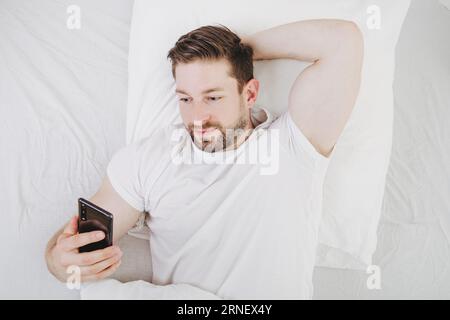 l'ossessione per il telefono cellulare costa sonno e tempo libero quando sdraiati a letto e dimentica il tempo Foto Stock