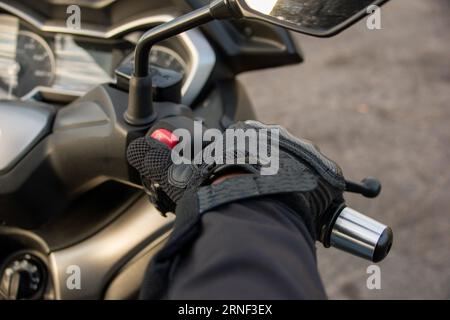 Primo piano della mano di un motociclista che preme il pulsante STOP della sua moto Foto Stock