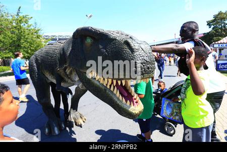(160819)-- TORONTO, Aug. 19, 2016 -- Visitors play with a costumed dinosaur at the 2016 Canadian National Exhibition in Toronto, Canada, Aug. 19, 2016. As one of the biggest exhibitions in Canada, this annual 18-day event which kicked off on Friday is expected to draw more than one million visitors from around the world. ) CANADA-TORONTO-CANADIAN NATIONAL EXHIBITION ZouxZheng PUBLICATIONxNOTxINxCHN   160819 Toronto Aug 19 2016 Visitors Play With a costumed Dinosaur AT The 2016 Canadian National Exhibition in Toronto Canada Aug 19 2016 As One of The Biggest Exhibitions in Canada This Annual 18 Foto Stock