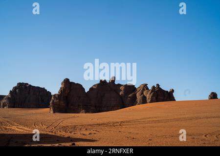 Vista nel deserto del Sahara di Tadrart rouge tassili najer nella città di Djanet, Algeria. Sabbia arancione colorata e montagne rocciose Foto Stock