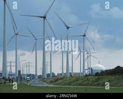 Molte turbine eoliche lungo la costa a Borssele, Zelanda, Paesi Bassi, con la cupola della centrale nucleare accanto ad esse. Foto Stock