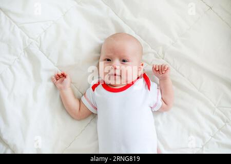 Il bambino di 2 mesi riposa sul letto, circondato da amore e cura. Tranquillità spensierata. Foto Stock