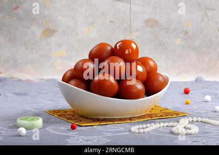 Dolce Gulab Jamun servito in una ciotola bianca, famosi dolci indiani e pakistani, sfondo isolato di studio interno Foto Stock