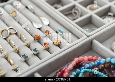 Organizzatore di gioielli in velluto grigio con diversi anelli, orecchini e bracciali in argento e oro per primo piano Foto Stock