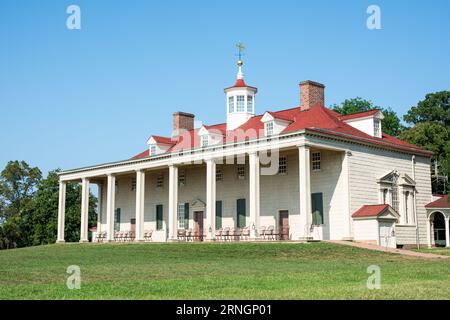 MOUNT VERNON, Virginia - l'esterno della residenza di George Washington di Mount Vernon si erge su un cielo azzurro. La struttura in legno a due piani, dipinta di bianco con persiane verdi, presenta la sua caratteristica piazza colonnata di fronte al fiume Potomac. Prati e giardini ben curati circondano la dimora storica. Foto Stock