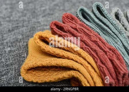Calzini in lana lavorati a mano di diversi colori su sfondo grigio, vista dall'alto Foto Stock