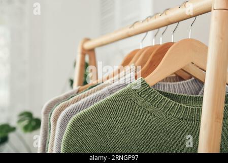 Maglioni multicolori in maglia a mano su appendiabiti in primo piano. Concetto di moda. Foto Stock