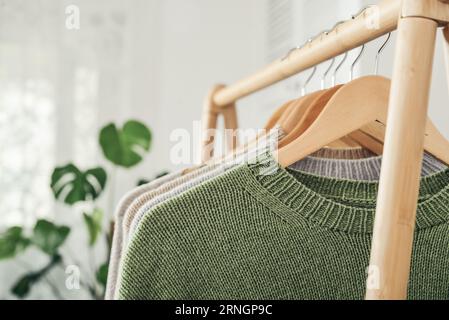 Maglioni multicolori in maglia a mano su appendiabiti in primo piano. Concetto di moda. Foto Stock