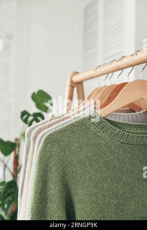 Maglioni multicolori in maglia a mano su appendiabiti in primo piano. Concetto di moda. Foto Stock