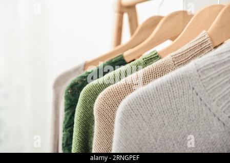 Maglioni multicolori in maglia a mano su appendiabiti in primo piano. Concetto di moda. Foto Stock