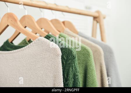 Maglioni multicolori in maglia a mano su appendiabiti in primo piano. Concetto di moda. Foto Stock