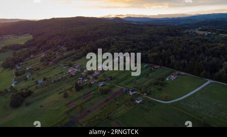 Pittoresco villaggio di Reber nella regione di dolenjska, in Slovenia, in una soleggiata sera al tramonto, con tipiche piccole case visibili o case del fine settimana chiamate Zidan Foto Stock