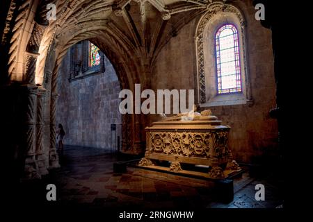Tomba del Monastero dos Jerónimos Bélem Lisbona Portogallo | BELÉM, Lisbona, Portogallo — Una tomba di pietra scolpita riposa sotto le volte a costoloni del Mosteiro dos Jerónimos (Monastero dos Jerónimos), un edificio che funziona tanto come pantheon nazionale quanto come luogo di culto. Il coro inferiore ospita le tombe neo-manueline di Vasco da Gama e del poeta Luís de Camões, scolpite su motivi di leoni e navi dallo scultore António Augusto da Costa Motta nel XIX secolo, mentre il re Manuel I e il re Giovanni III giacciono altrove nella chiesa. Foto Stock
