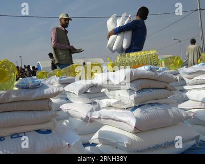 (161025) -- QAYYARAH, 25 ottobre 2016 -- le persone del campo di Jadah ricevono cibo nella città di Qayyarah nel sud di Mosul, Iraq, il 25 ottobre 2016. L'Ufficio delle Nazioni Unite per il coordinamento degli affari umanitari (OCHA) Stephane Dujarric ha detto ai giornalisti martedì che quasi 9.000 persone sono sfollate internamente a seguito dell'operazione militare di Mosul in Iraq. Lise grande, coordinatore umanitario delle Nazioni Unite per l'Iraq, ha detto che le operazioni militari per riprendere Mosul potrebbero innescare la più grande crisi umanitaria nel 2016, poiché la situazione della sicurezza nell'area limita la capacità delle agenzie di aiuto di fornire aiuto. ) IRAQ-QAYARA Foto Stock