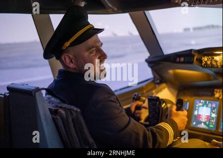 L'uomo caucasico sorrise mentre era seduto in un simulatore di volo. Pilota nel cockpit. Foto Stock