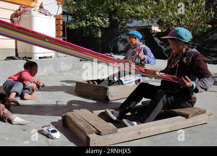 DULONGJIANG, 23 novembre 2016 -- Daiqie (R) di 77 anni con tatuaggio facciale etnico e tappeto di tessitura li Wenshi di 73 anni nel villaggio di Dizhengdang di Dulongjiang Township, nella provincia dello Yunnan della Cina sud-occidentale, 23 novembre 2016. Dulongjiang Township è la patria di persone del gruppo etnico Dulong. A causa delle condizioni naturali abominevoli, l'economia locale non era sviluppata in passato. Dopo anni di sviluppo, le strade sono state pavimentate e le abitazioni moderne sono state costruite per sostituire le case coperte di paglia. L'assicurazione medica rurale ha coperto il 98% degli abitanti del villaggio e tutti i bambini in età scolare hanno ricevuto l'istruzione Foto Stock
