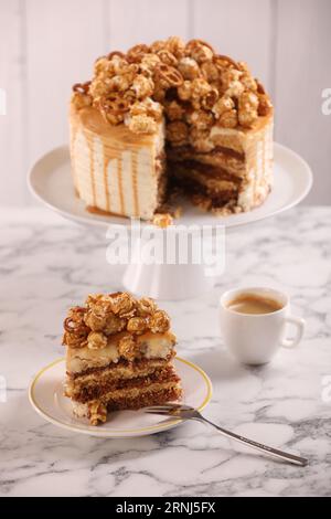 Gocciolatoio al caramello decorato con popcorn e pretzel serviti su un tavolo in marmo bianco Foto Stock