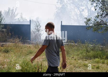 Un residente locale cammina lungo la strada mentre il fumo sale dopo che un bombardamento russo ha colpito una casa privata a Huliaipole. Nell'Oblast di Zaporizhzhia, gli scioperi russi hanno ferito una donna di 52 anni e un uomo di 67 anni a Huliaipole, il governatore Yurii Malashko Said. Malashko ha aggiunto che gli attacchi russi hanno colpito 21 insediamenti in tutta la regione nell'ultimo giorno (agosto 31). Huliaipole si trova vicino al fronte nella regione di Zaporizhzhia, che ha visto pesanti combattimenti durante la controffensiva Ucraina contro le forze russe. La città ha subito quotidianamente attacchi di razzi e artiglieria da parte delle forze russe. Foto Stock