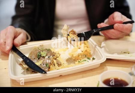 (170425) -- NEW YORK, 25 aprile 2017 -- Un cliente ha Jianbing del signor Bing in UrbanSpace food Court a New York, Stati Uniti, 17 aprile 2017. UrbanSpace nel centro di New York è un luogo dove i collari bianchi vengono a pranzo durante i loro giorni lavorativi. Negli ultimi mesi, i clienti si sono sempre allineati prima di un chiosco sotto uno striscione con caratteri cinesi. Quello che questo chiosco vende è un autentico cibo cinese nel nord della Cina -- Jianbing, o crepe cinese. Il chiosco è marchiato Mr. Bing ed è di proprietà di Brian Goldberg, che è nato e cresciuto a New York. Goldberg è molto coinvolto con il cinese Foto Stock