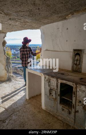 Donna che guarda la finestra all'interno delle grotte di Argueda con pareti bianche, in Spagna Foto Stock