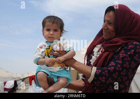 (170513) -- MOSUL, 13 maggio 2017 -- Una donna tiene suo figlio nel campo Hassansham U2, circa 30 km a est di Mosul, in Iraq, il 13 maggio 2017. Il campo ha una capacità di ospitare più di 9.000 persone quando è completamente occupato. Secondo le autorità irachene, più di 630.000 persone sono state sfollate da Mosul e dalle aree circostanti dall'ottobre 2016, quando è iniziata l'operazione militare. Ciò include più di 434.000 sfollati dalla parte occidentale di Mosul dalla metà di febbraio di quest'anno. ) IRAQ-MOSUL-HASSANSHAM U2 CAMP WeixYudong PUBLICATIONxNOTxINxCHN Mosul 13 maggio 2017 una donna tiene il suo bambino in U2 Camp Abou Foto Stock