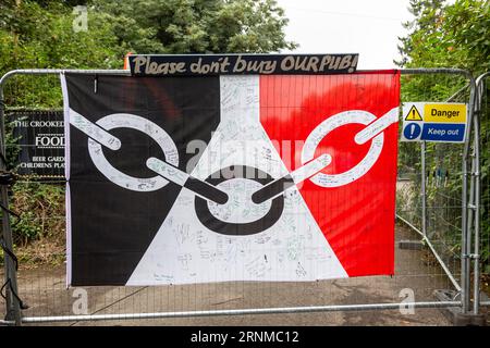 Himley, Staffordshire, Regno Unito. 2 settembre 2023. Quattro settimane dopo che il famoso pub Crooked House è bruciato, i cartelli di protesta e la bandiera del Paese Nero sono esposti a sostegno della ricostruzione dell'edificio storico nella stessa posizione. La bandiera del Paese Nero viene firmata e disegnata con messaggi di supporto. dalla gente del posto. Crediti: Peter Lopeman/Alamy Live News Foto Stock