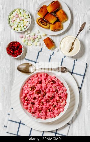 insalata cremosa di mirtilli rossi con mini marshmallow, mela fresca e noci pecan in ciotola bianca su tavolo di legno bianco con dolci alla cannella, ricetta americana, ve Foto Stock