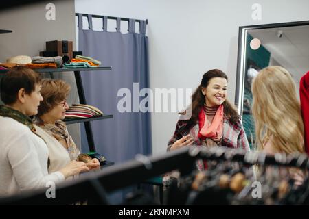 Donna anziana che raccoglie vestiti in un negozio. Foto Stock