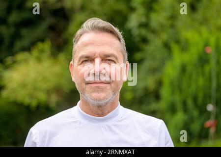 Ritratto ravvicinato di un attraente uomo di mezza età dei suoi 50 anni con un aspetto arrogante e snootato mentre si trova in giardino Foto Stock