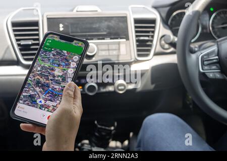 Una donna ha in mano un telefono con navigatore in un'auto in movimento guidata da un uomo Foto Stock