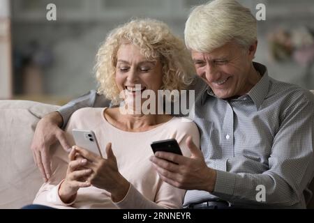 Marito e moglie felici e anziani che hanno uno smartphone, leggono messaggi Foto Stock