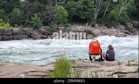 Una vista panoramica di due persone sedute vicino al fiume Niagara nel Whirlpool State Park, Stati Uniti Foto Stock