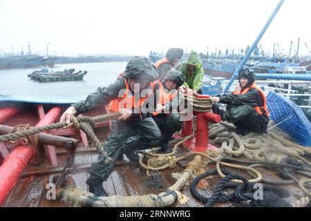 (170730) -- JINJIANG, 30 luglio 2017 -- i poliziotti aiutano i pescatori locali a rafforzare le barche da pesca in un molo a Jinjiang, nella provincia del Fujian della Cina sudorientale, 30 luglio 2017. Il tifone Nesat, il nono tifone dell'anno, sbarcò a Fujian domenica mattina. Senza tregua, il tifone Haitang, il decimo tifone dell'anno, avrebbe dovuto atterrare nel sud di Taiwan domenica notte e fare un secondo atterraggio da qualche parte tra Xiapu e Jinjiang nella provincia di Fujian lunedì mattina, secondo il Centro meteorologico Nazionale. I due tifoni avrebbero dovuto portare piogge pesanti e forti galee al coa Foto Stock