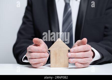 Casa in legno protetta da uomini d'affari, concetto di sicurezza assicurativa Foto Stock