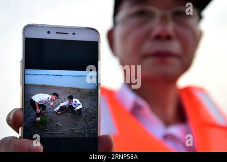 (170811) -- ANQING, 11 agosto 2017 -- un poliziotto ausiliario mostra una scena di morte di una focaccia senza pinne attraverso un'applicazione telefonica nella riserva naturale di foschia senza pinne ad Anqing, nella provincia di Anhui nella Cina orientale, 10 agosto 2017. Una brigata ausiliaria di pattuglia, tra cui 6 ex pescatori, ha iniziato la sua missione nel giugno 2017 proteggendo le 60 focene senza alette lungo la sezione lunga 60 chilometri del fiume Yangtze nella provincia. L'applicazione telefonica viene utilizzata nelle loro missioni di routine per monitorare e osservare la vita dei mammiferi simili a delfini, fornire la protezione necessaria e monitorare gli inquinanti e i malati Foto Stock