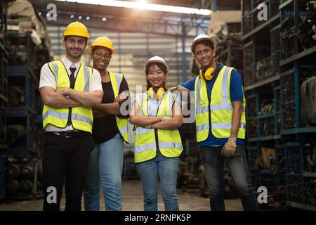 gruppo ritratto di un dipendente ingegnere gruppo di personale diversity lavoratori insieme in un'officina di fabbrica di metalli sporchi Foto Stock